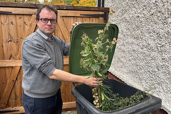 Henry Vann putting vegetation into a green lidded bin