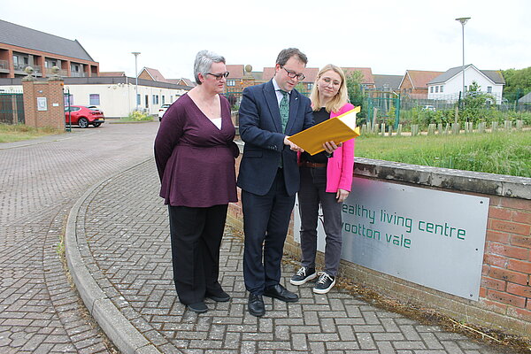 Outside Wootton healthy living centre.  Three people looking at yellow clipboard.